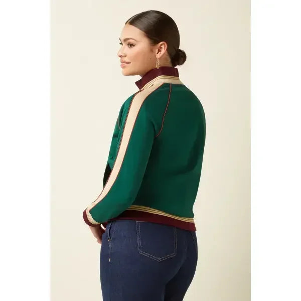 Woman wearing green and burgundy jacket with striped sleeves and dark blue jeans