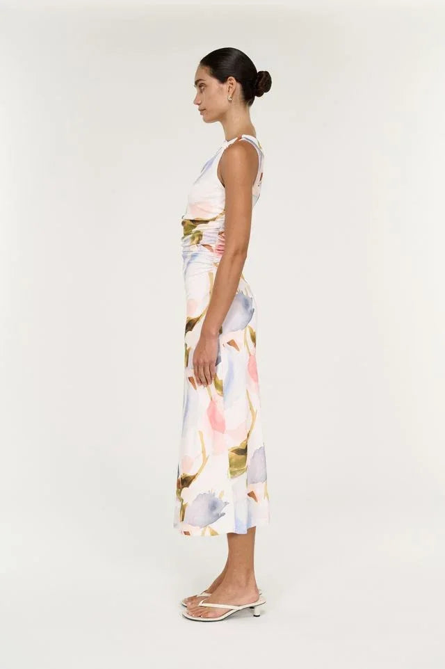 Woman wearing a white midi dress with a colorful floral print and white strappy sandals.
