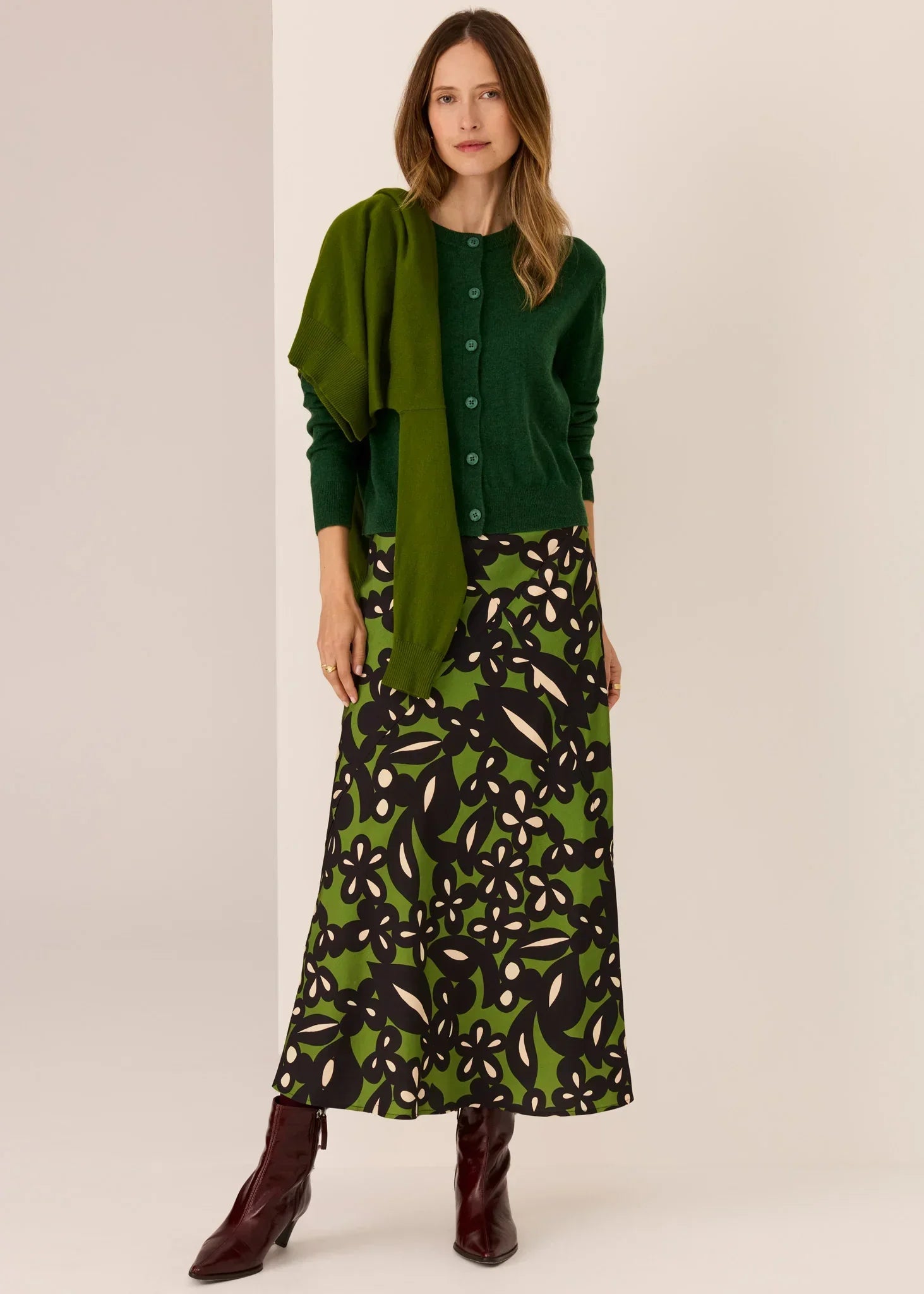 Woman in green cardigan, floral midi skirt, and burgundy boots — women's fashion outfit