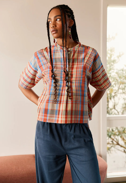 Woman wearing the NANCYBIRD Monica Top in Coast Check with blue trousers.