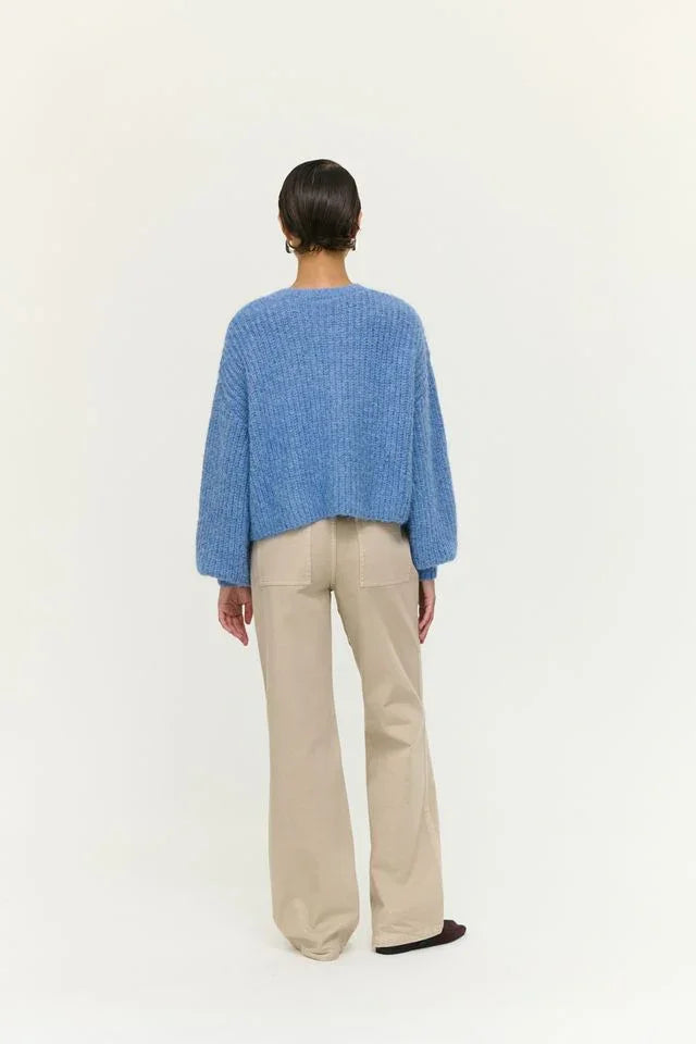Woman wearing blue knit sweater and beige wide-leg pants, back view