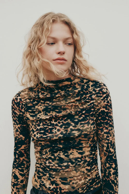 Woman wearing leopard print long sleeve top with ruched detail, stylish women's fashion