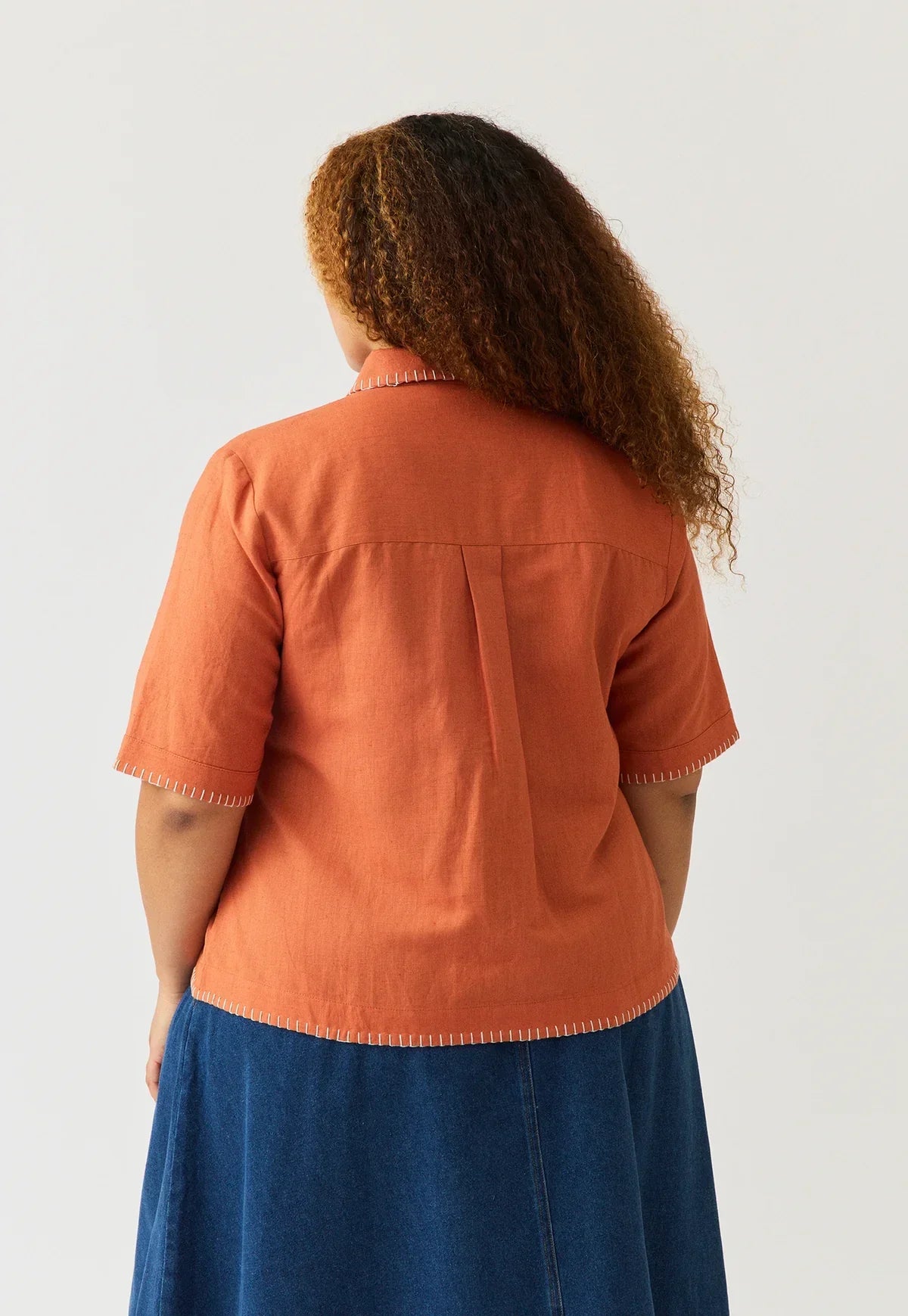 Back view of a person wearing a NANCYBIRD Summer Shirt in Blossom Appliqué and a denim skirt