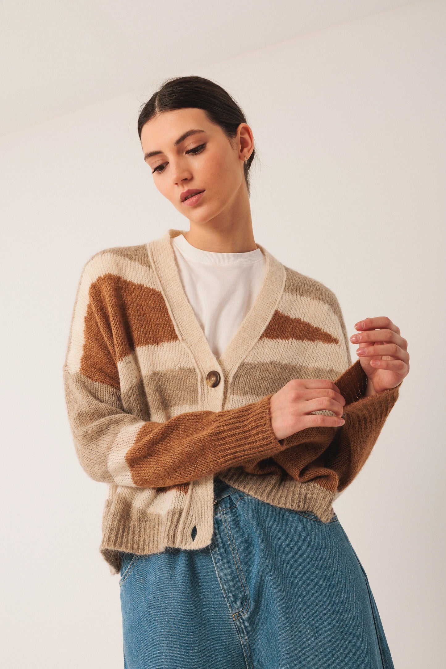 Woman wearing cozy brown and cream striped cardigan with denim skirt, stylish women's fashion
