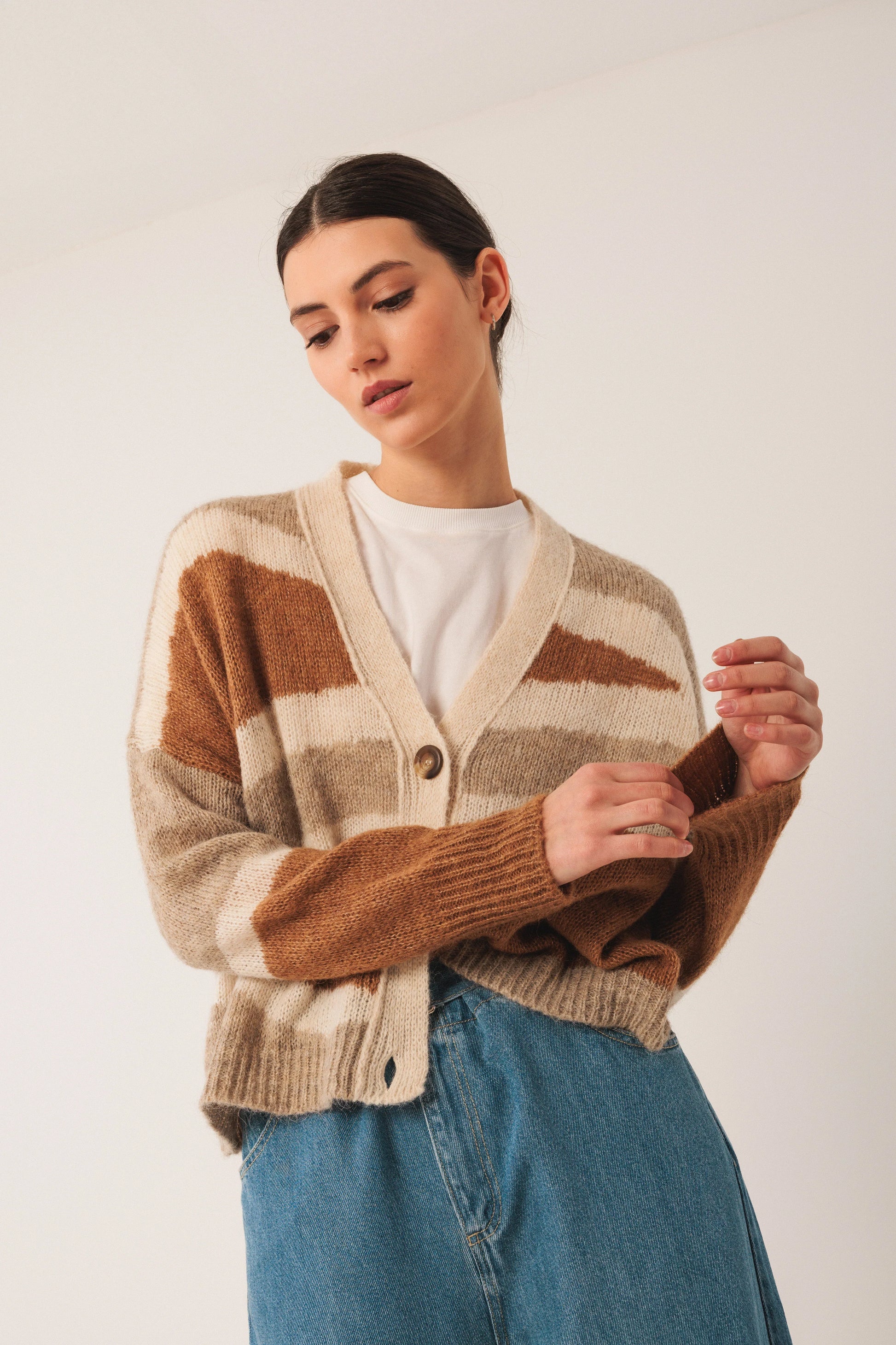 Woman wearing cozy brown and cream striped cardigan with denim skirt, stylish women's fashion