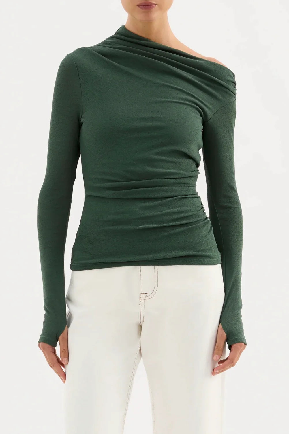 Woman wearing dark green long sleeve asymmetric top and white pants, fashion boutique style
