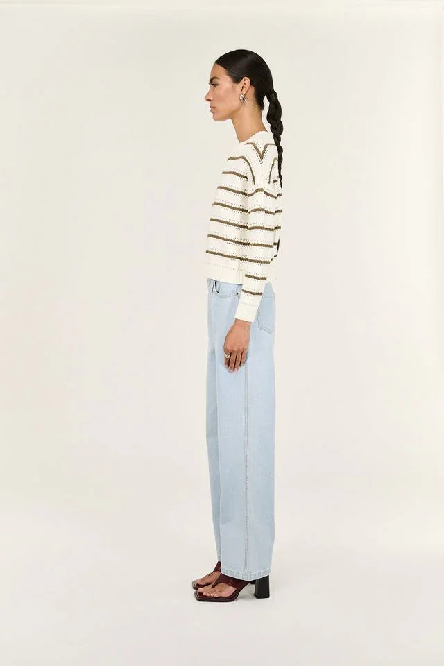Woman in striped knit sweater and light blue wide-leg jeans, side profile