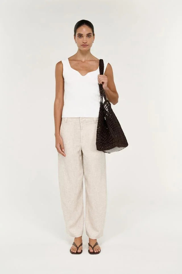 Woman wearing STAPLE THE LABEL Neve Linen Barrel Leg Pants in beige with a white top.
