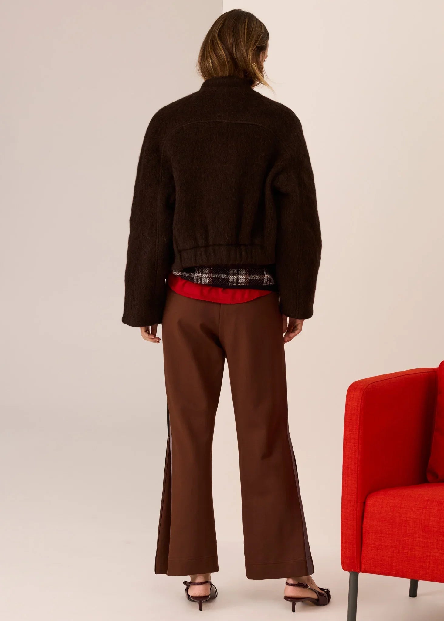 Brown fuzzy cropped jacket with plaid trim, paired with wide-leg trousers and heels