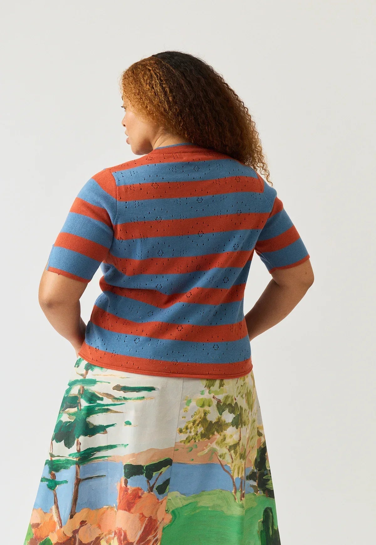 Back view of a woman wearing the NANCYBIRD Rana Knit Tee in Terracotta Stripe.