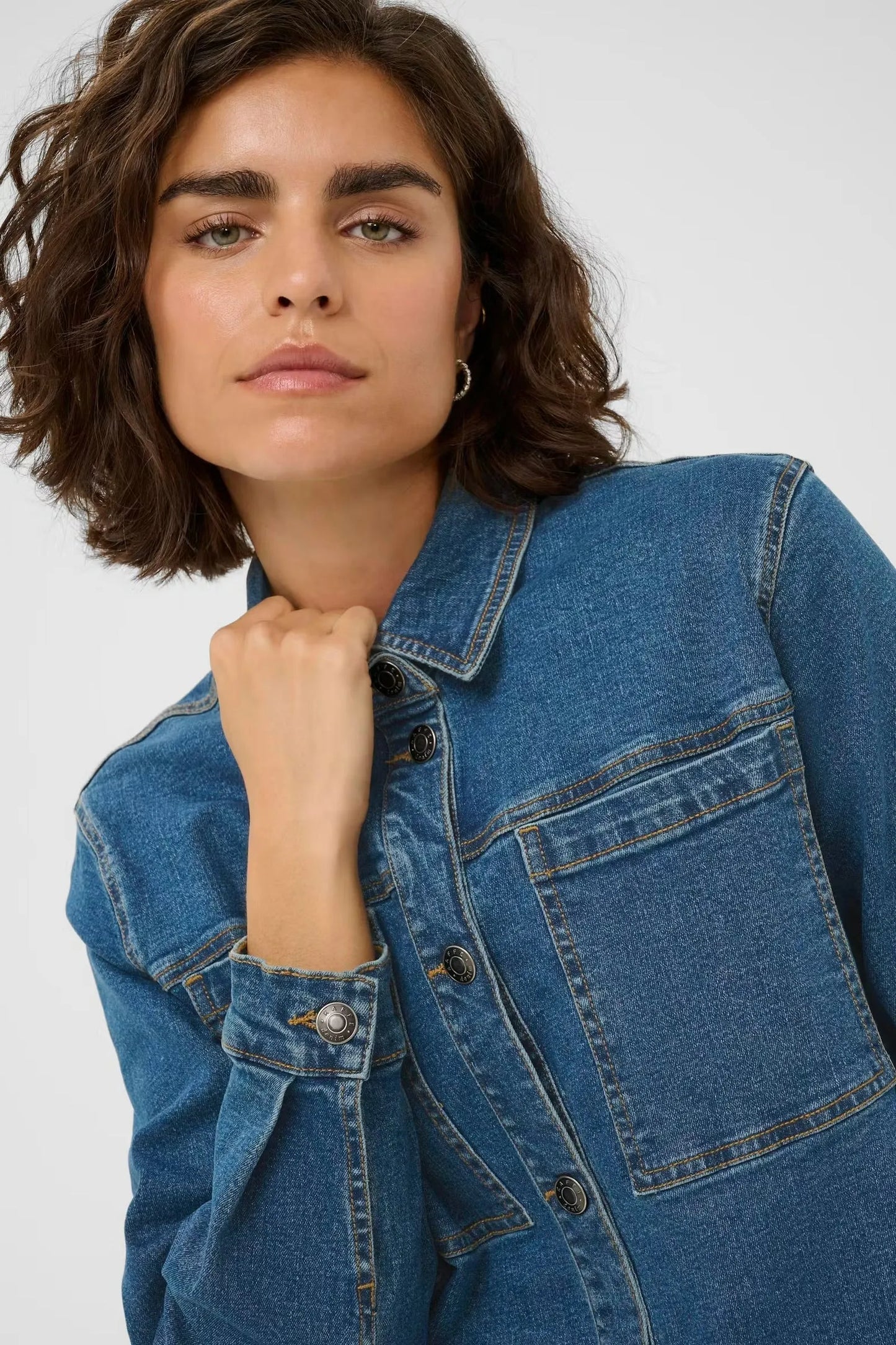 Woman wearing classic blue denim jacket with button front and chest pockets, stylish women's fashion
