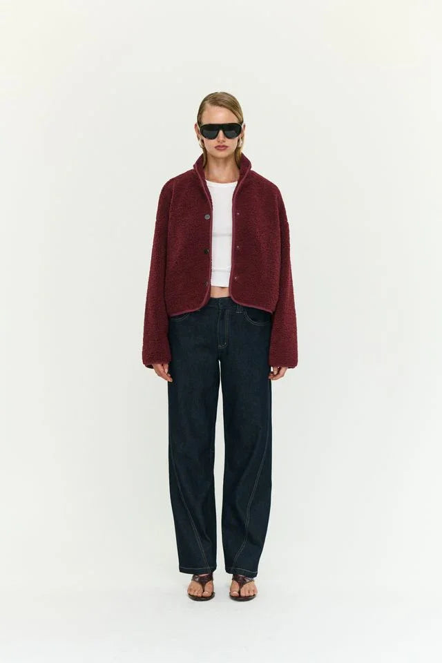 Woman in burgundy teddy jacket, white top, wide-leg jeans, and sandals — women's fashion