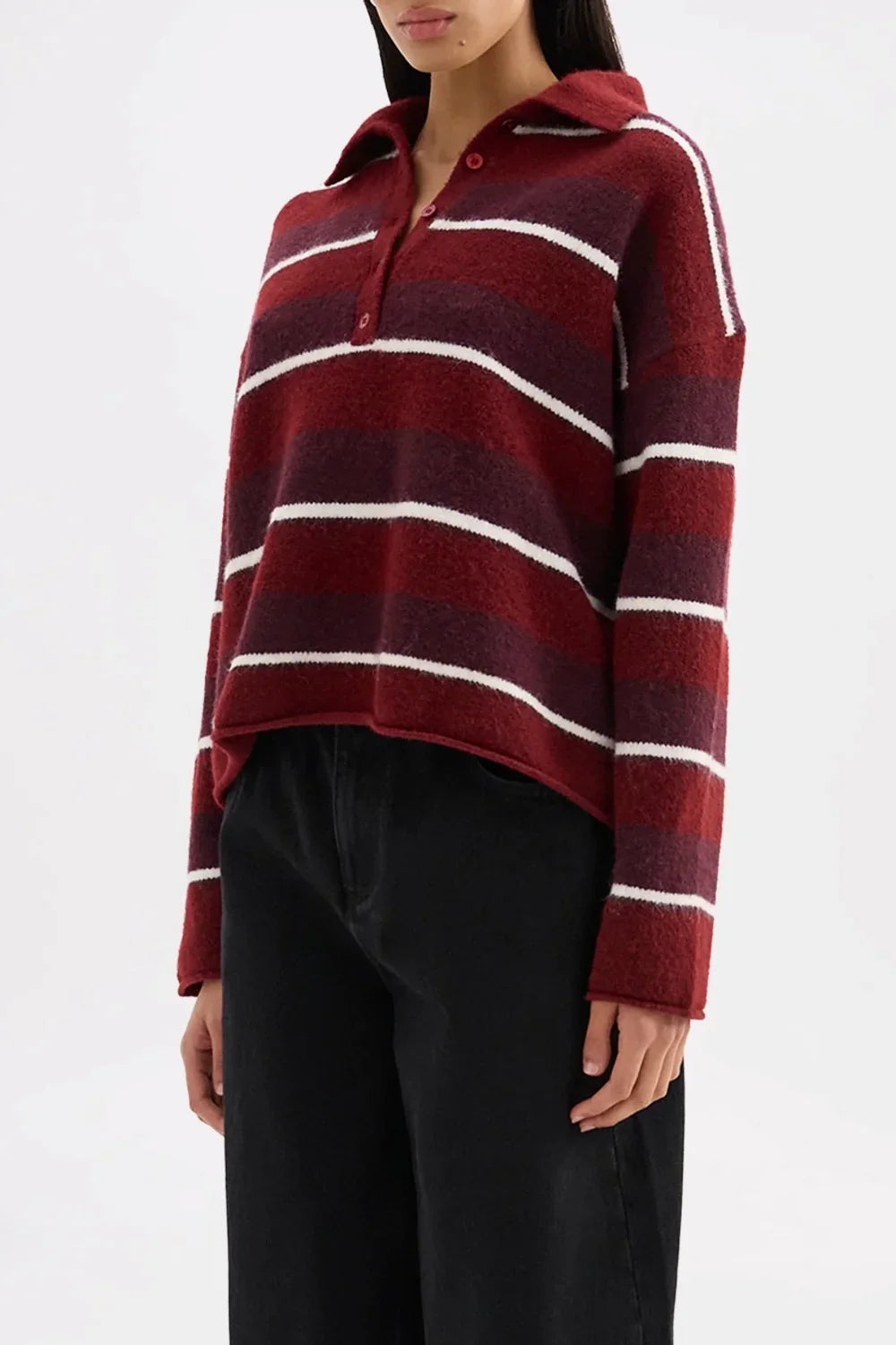 Woman wearing a red and purple striped polo neck sweater with black pants
