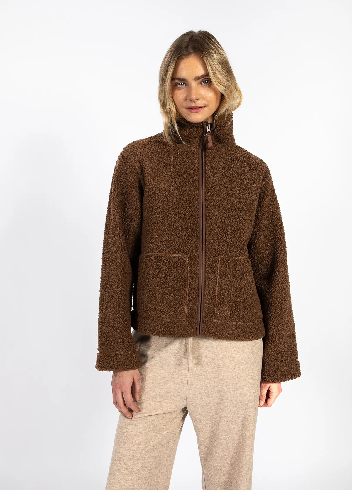 Woman modeling a brown fleece zip-up jacket and beige pants from The Tartan Fox boutique