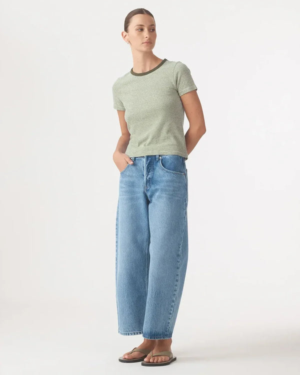 Woman wearing Nobody Denim Baby Tee in Olive Stripe and light blue wide-leg jeans.