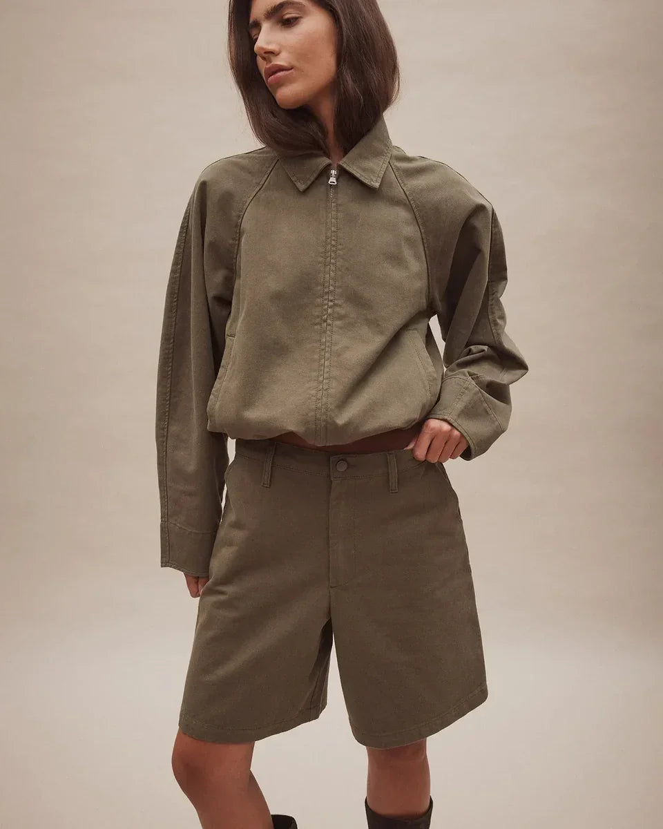 Woman wearing Nobody Denim Rowan Bermuda Shorts in Safari with a matching olive jacket.