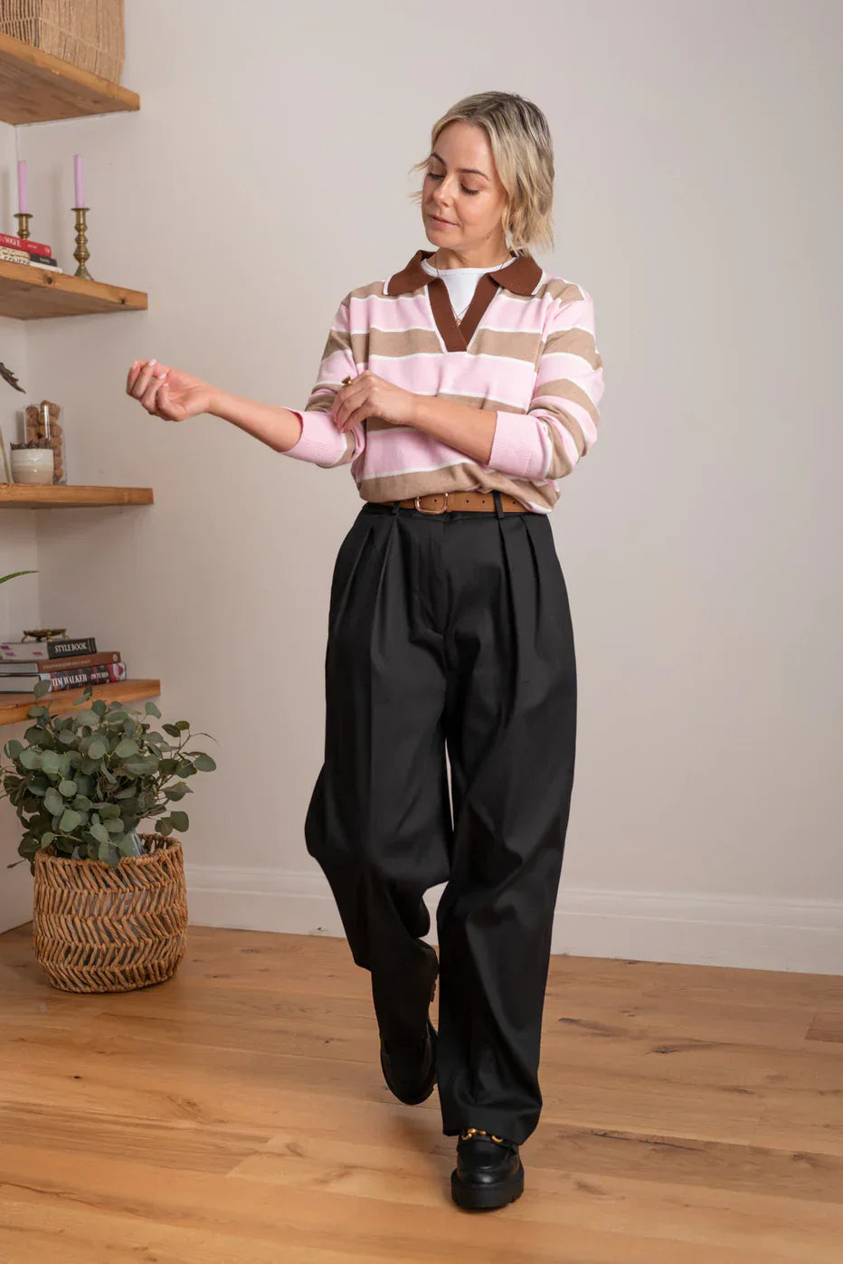 Woman wearing pink and tan striped sweater with black wide-leg trousers, casual chic style