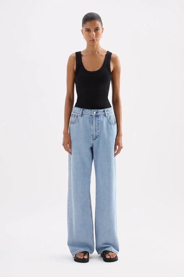 Woman wearing a Nude Lucy Organic Rib Singlet in Black and light blue wide-leg jeans.