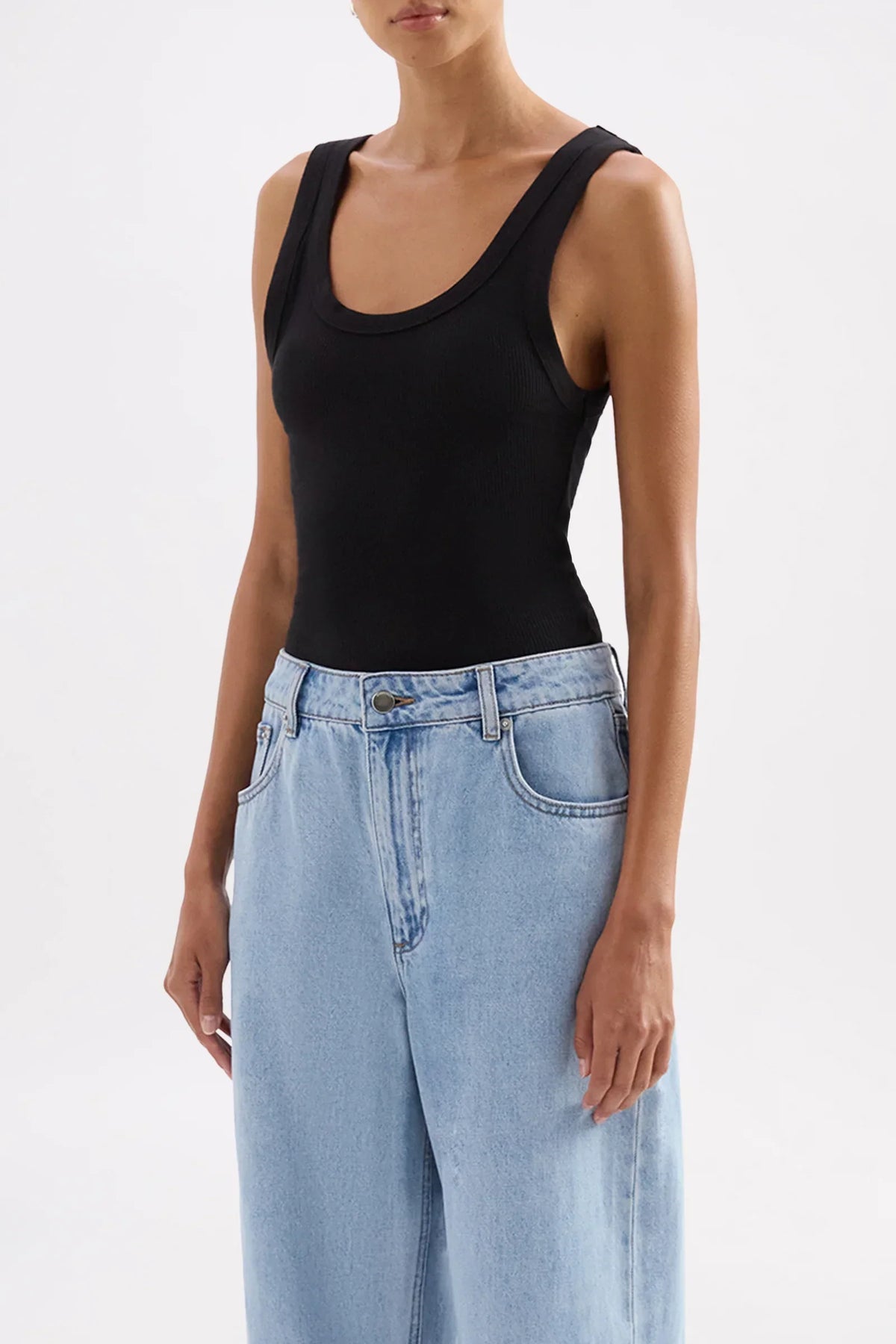 Woman wearing Nude Lucy Organic Rib Singlet in Black paired with light blue jeans