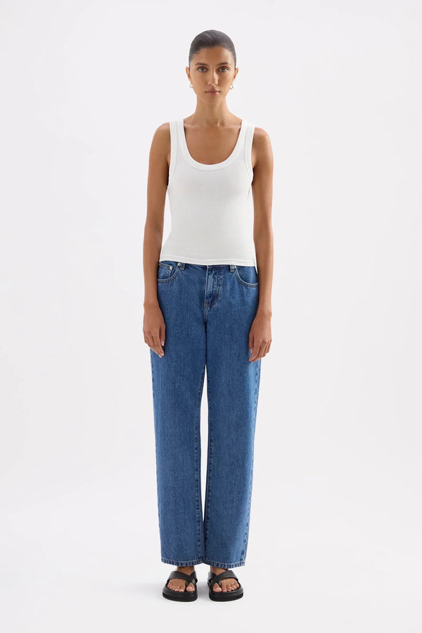 Woman wearing a Nude Lucy Organic Rib Singlet in white paired with blue jeans.