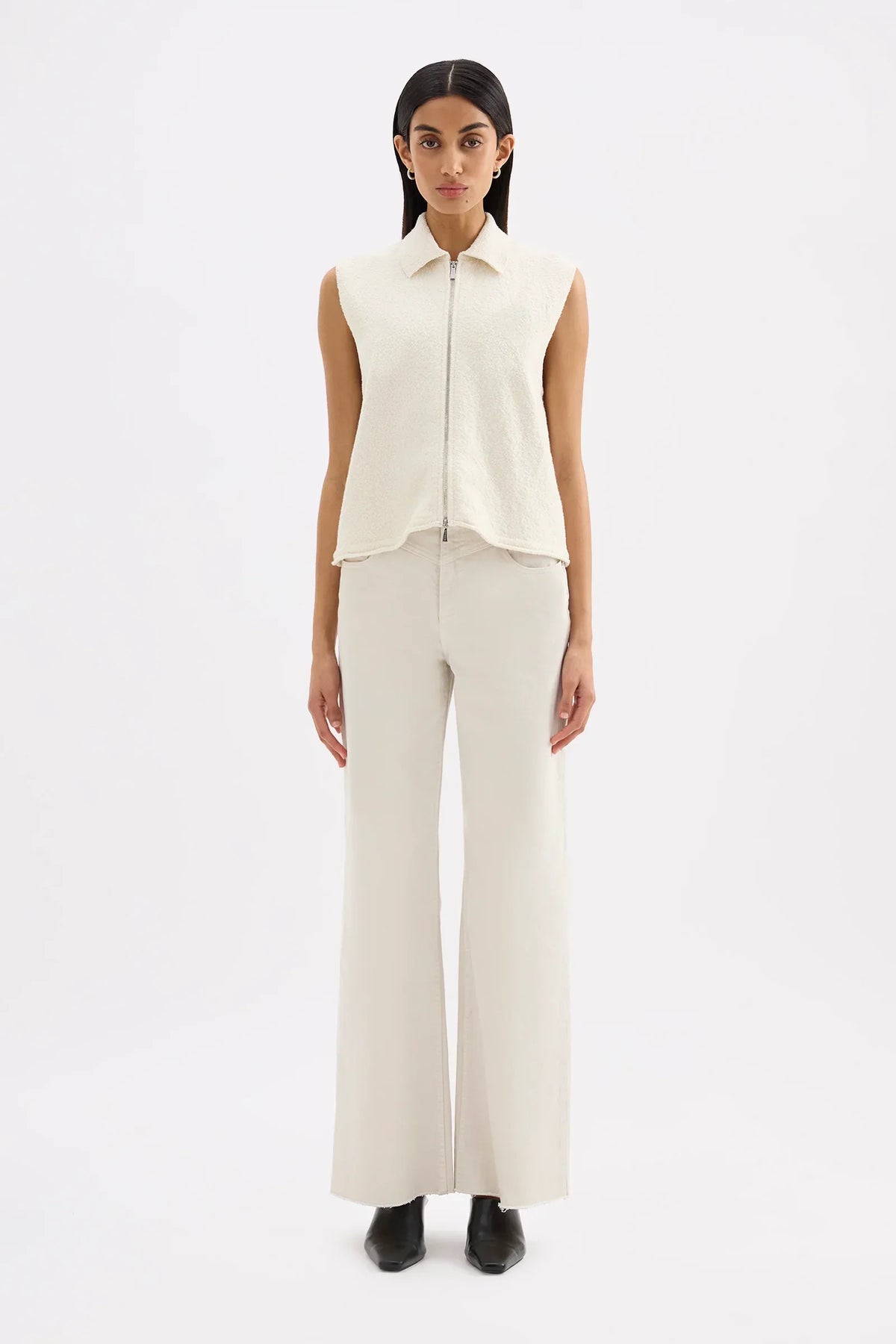 Model wearing Nude Lucy Riella Knit Vest in Dune paired with off-white wide-leg trousers.