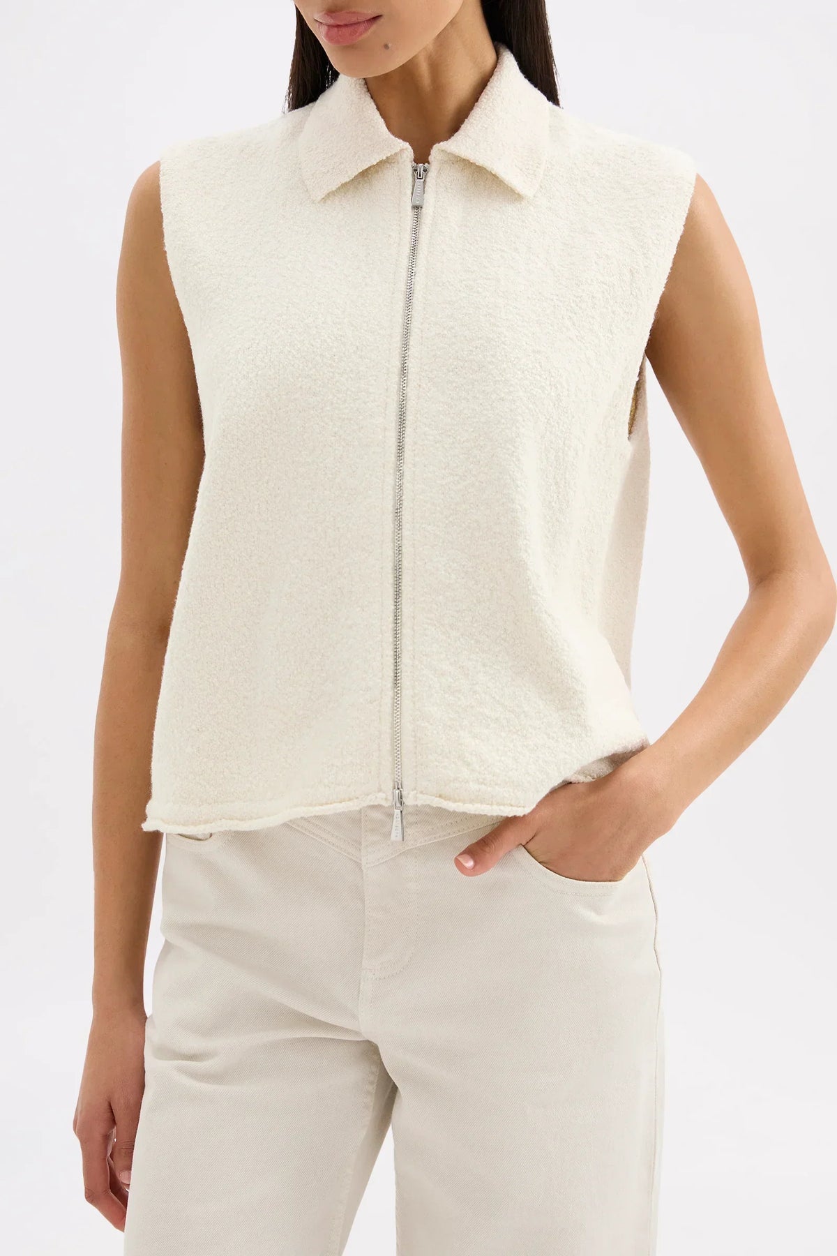 Woman wearing the Nude Lucy Riella Knit Vest in Dune with a zip front and collar.