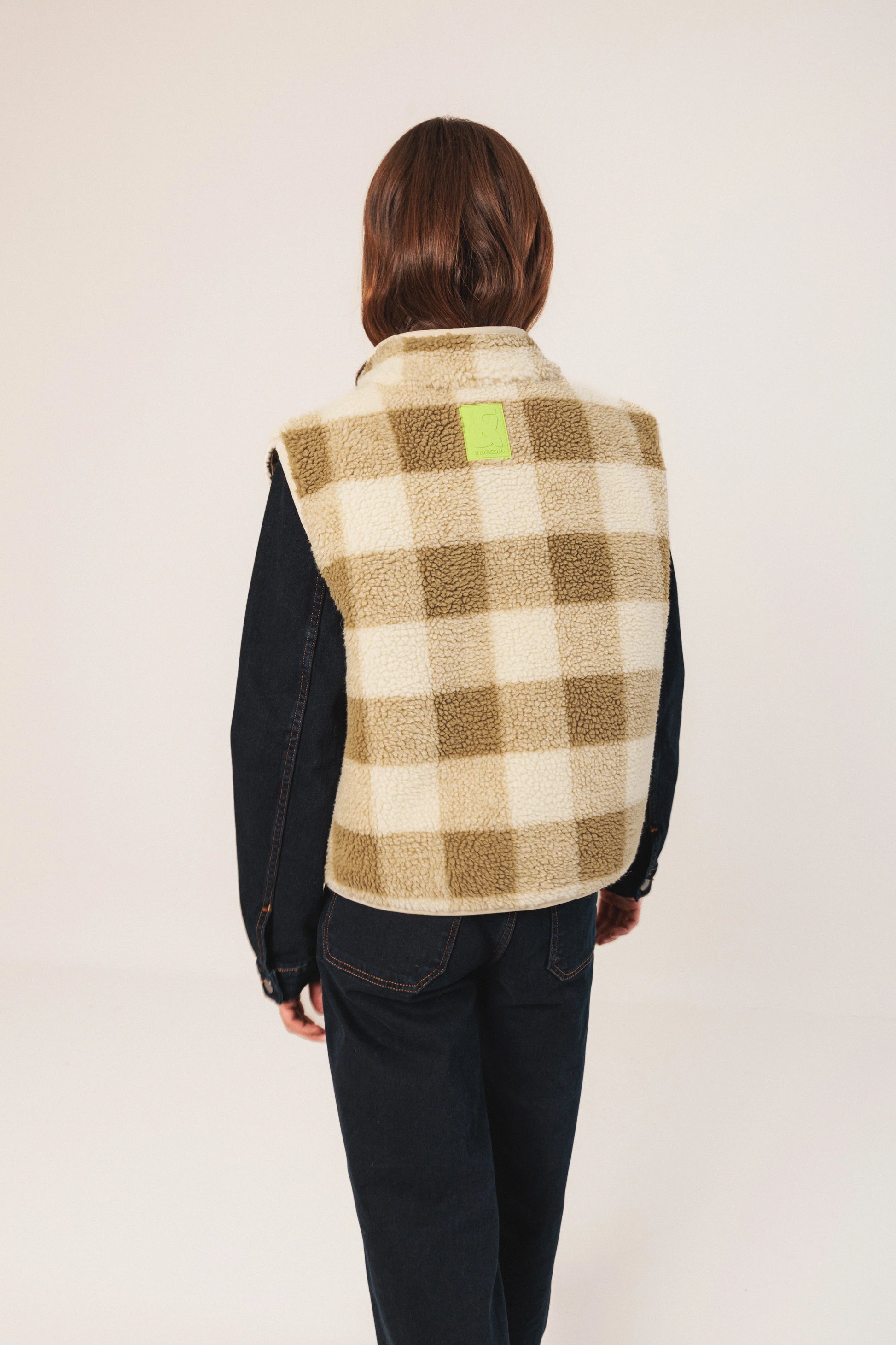 Woman wearing cozy plaid sherpa vest with denim sleeves, back view