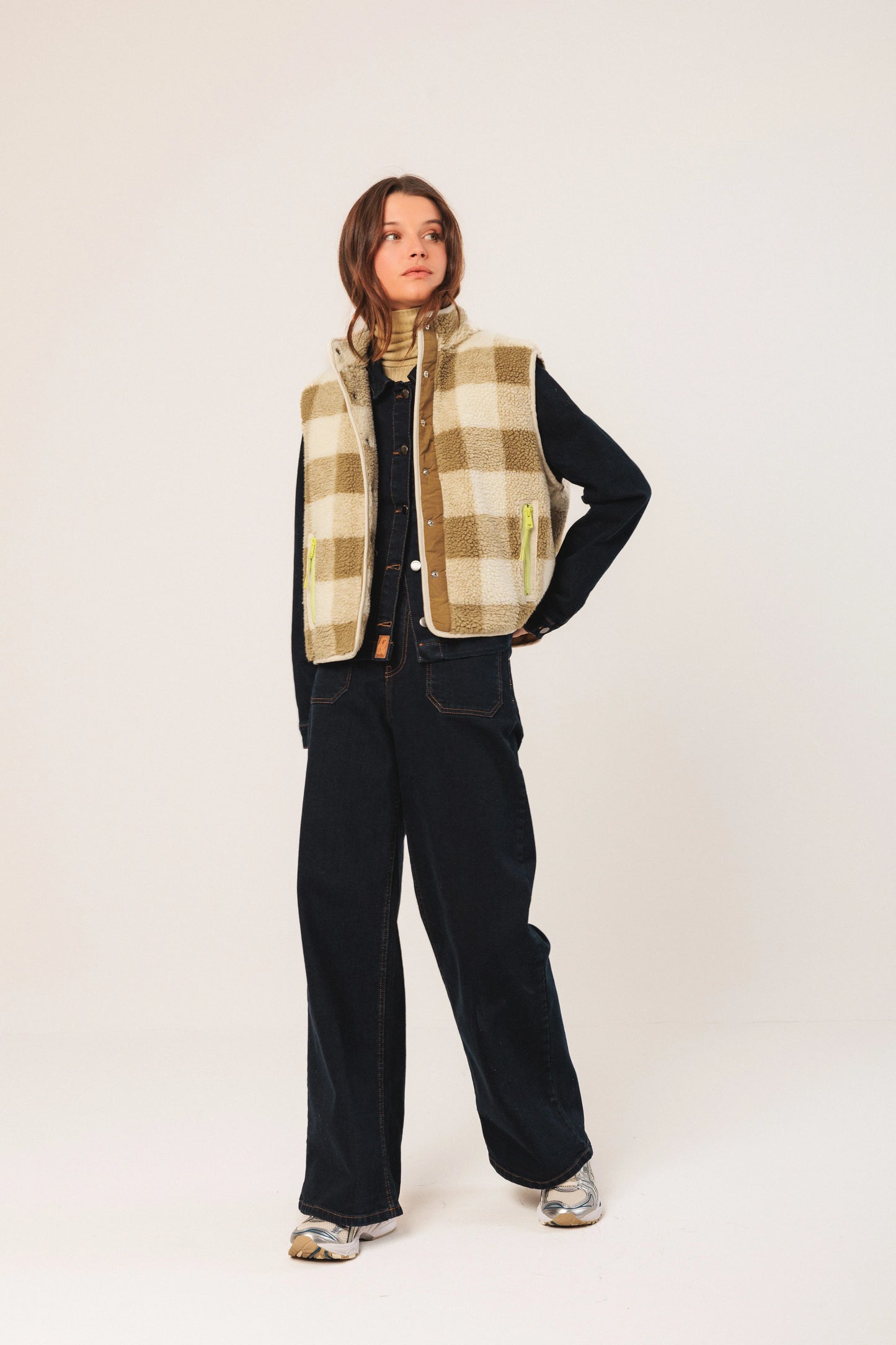 Woman in plaid shearling vest, denim shirt, wide-leg jeans, and sneakers for women's fashion