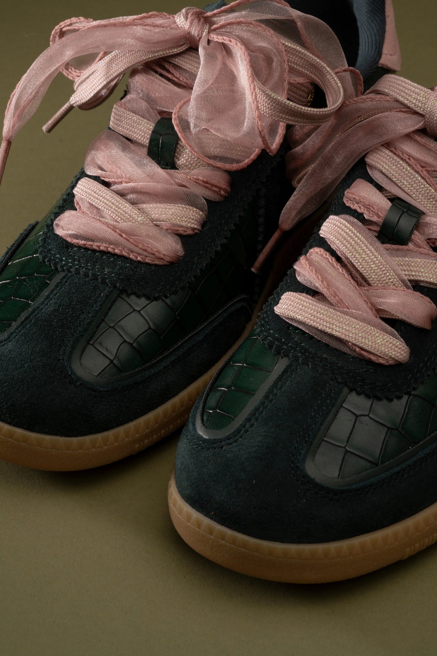 Dark green suede sneakers with pink shimmer laces and croc-textured details, stylish everyday footwear