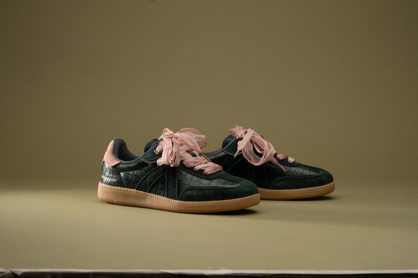 Dark green croc-texture sneakers with pink ribbon laces and gum soles, stylish everyday footwear
