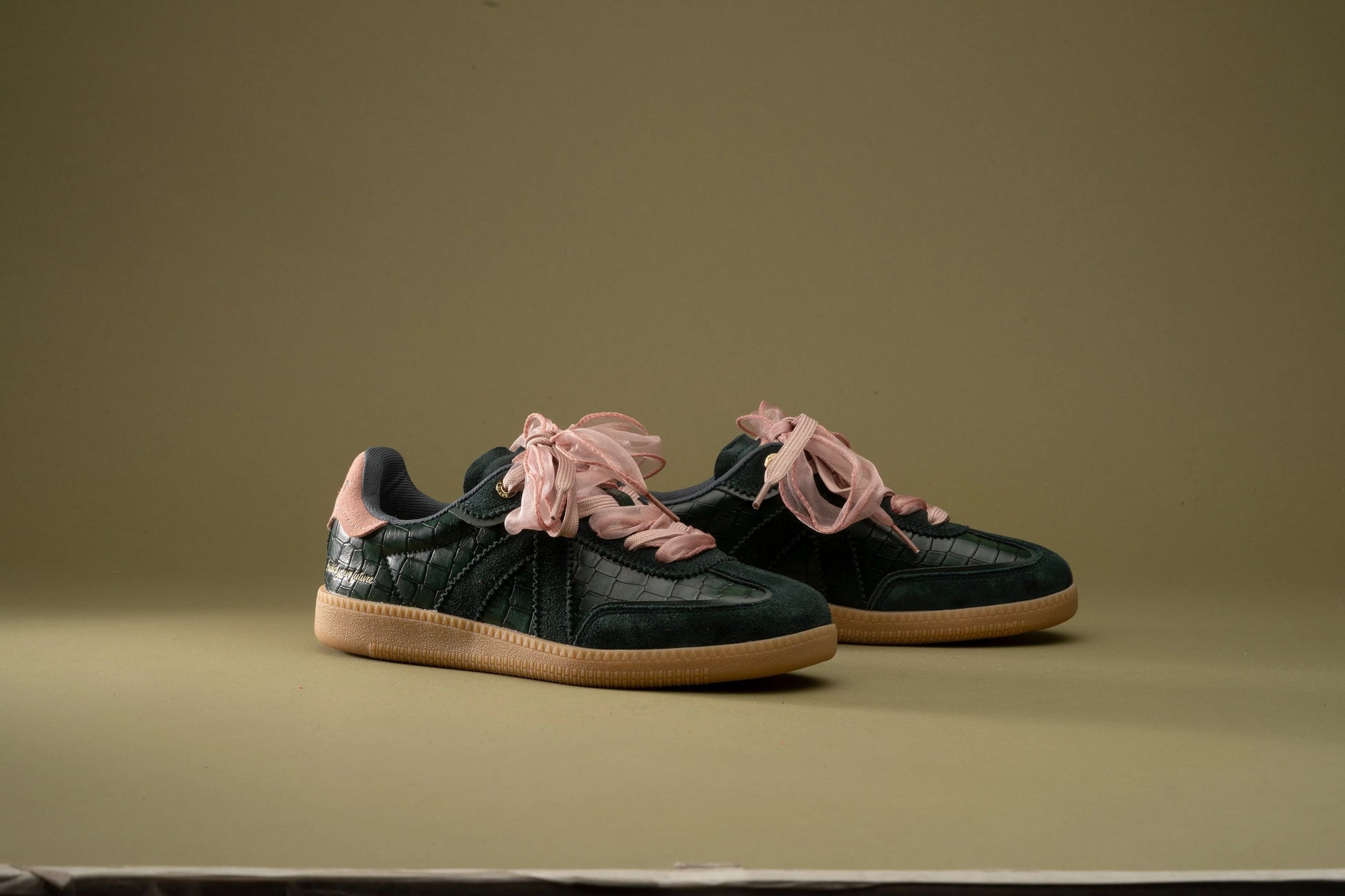 Dark green croc-texture sneakers with pink ribbon laces and gum soles, stylish everyday footwear