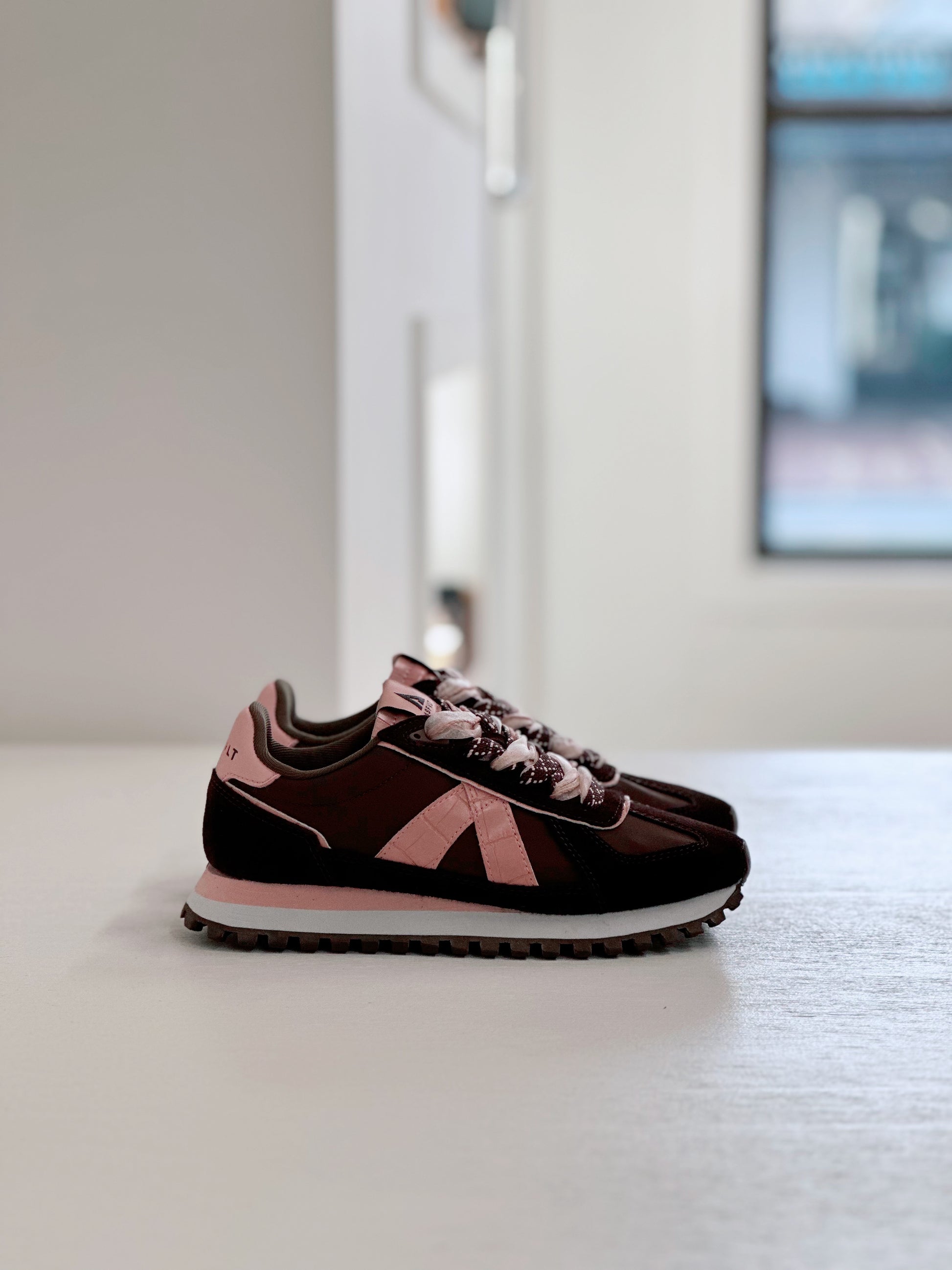 Brown and pink retro running sneakers with textured side panels and chunky sole, styled on a light surface.