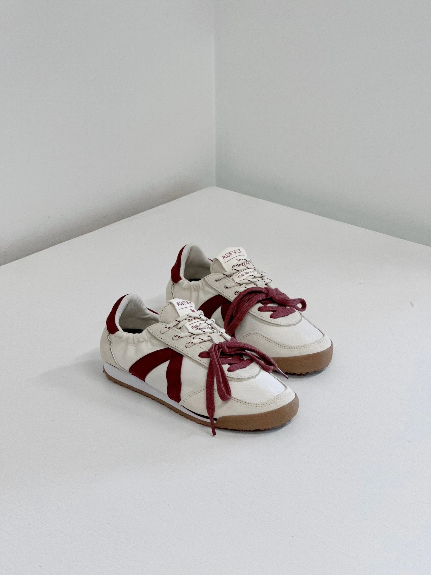 White and burgundy retro sneakers with bold stripes and gum soles, styled for everyday wear.