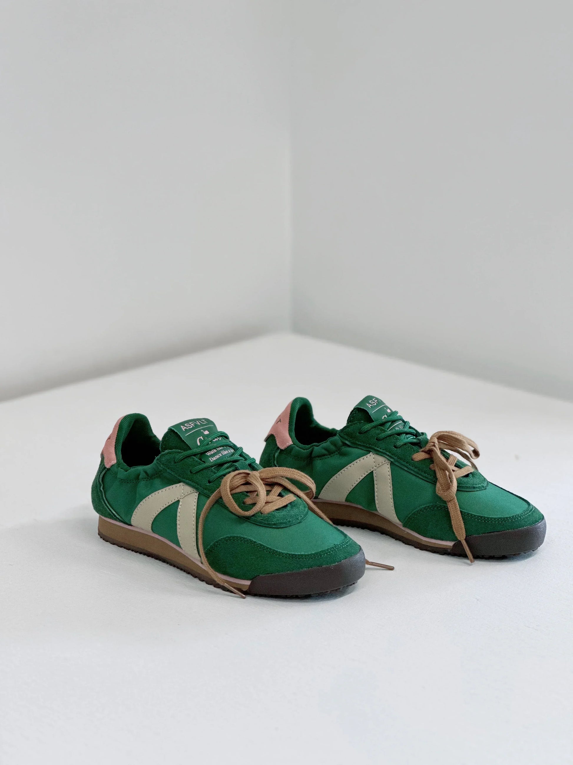 Green canvas sneakers with beige stripe, tan laces, and pink heel tab for everyday wear