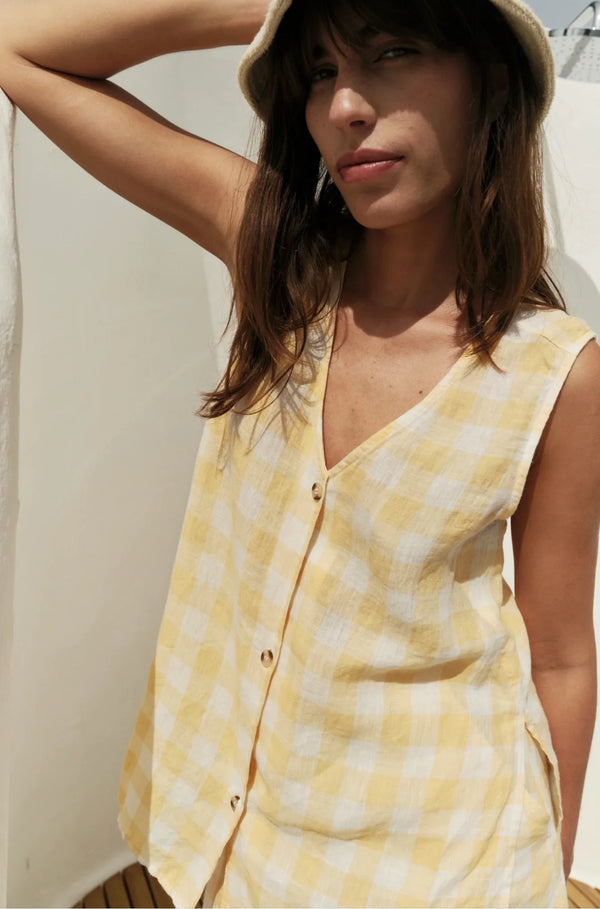 Yellow and white checkered sleeveless top with button front, styled with a hat for summer fashion