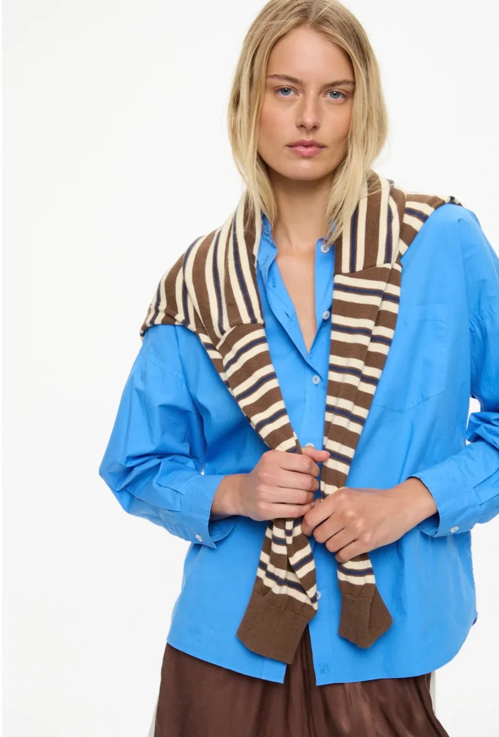 Woman wearing striped knit scarf over blue shirt, stylish women's fashion accessory