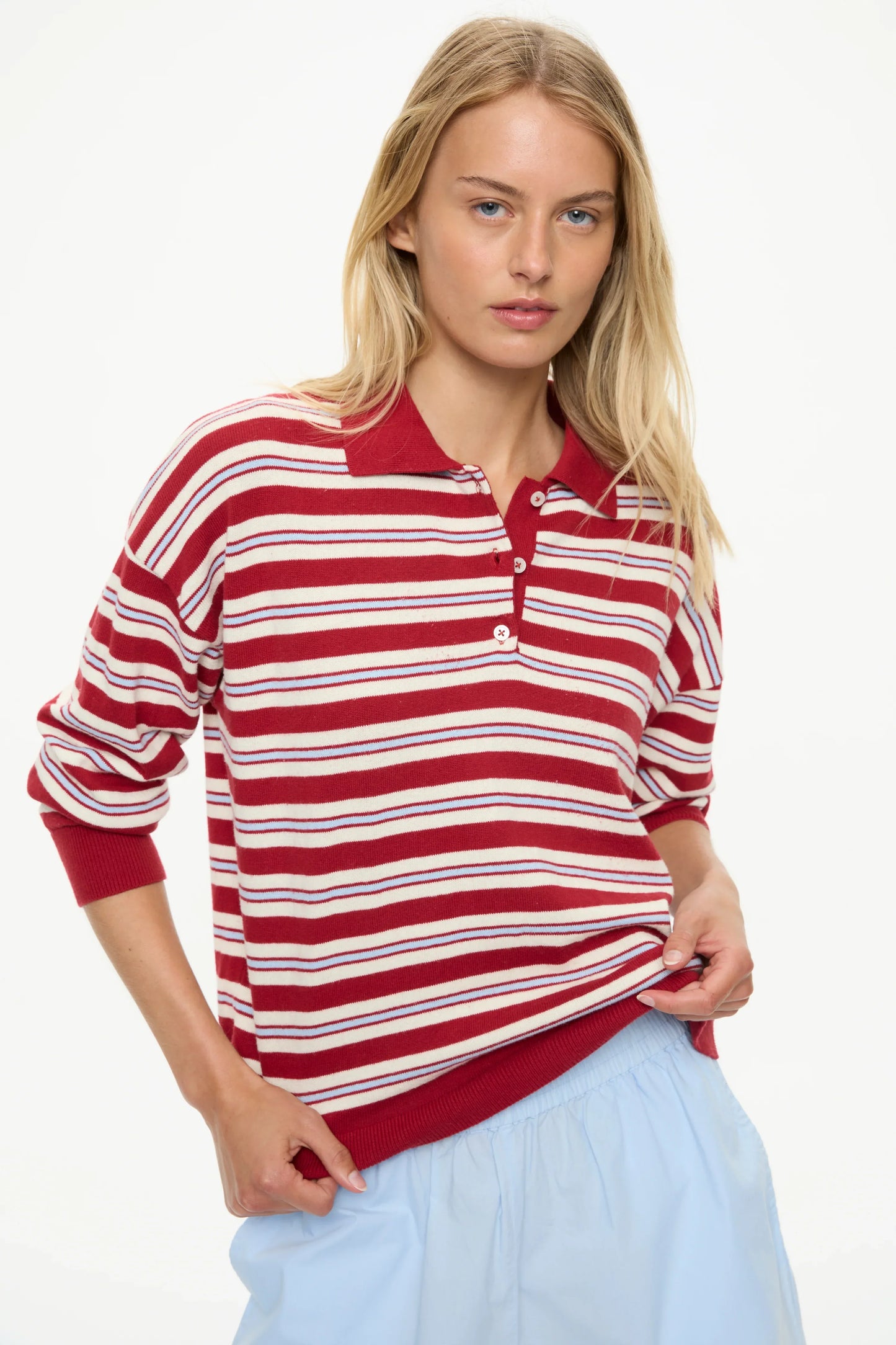 Woman wearing red and white striped long sleeve polo shirt with light blue accents, paired with blue skirt.
