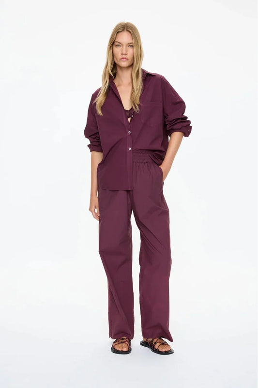 Woman in burgundy button-up shirt and wide-leg pants, casual women's fashion outfit