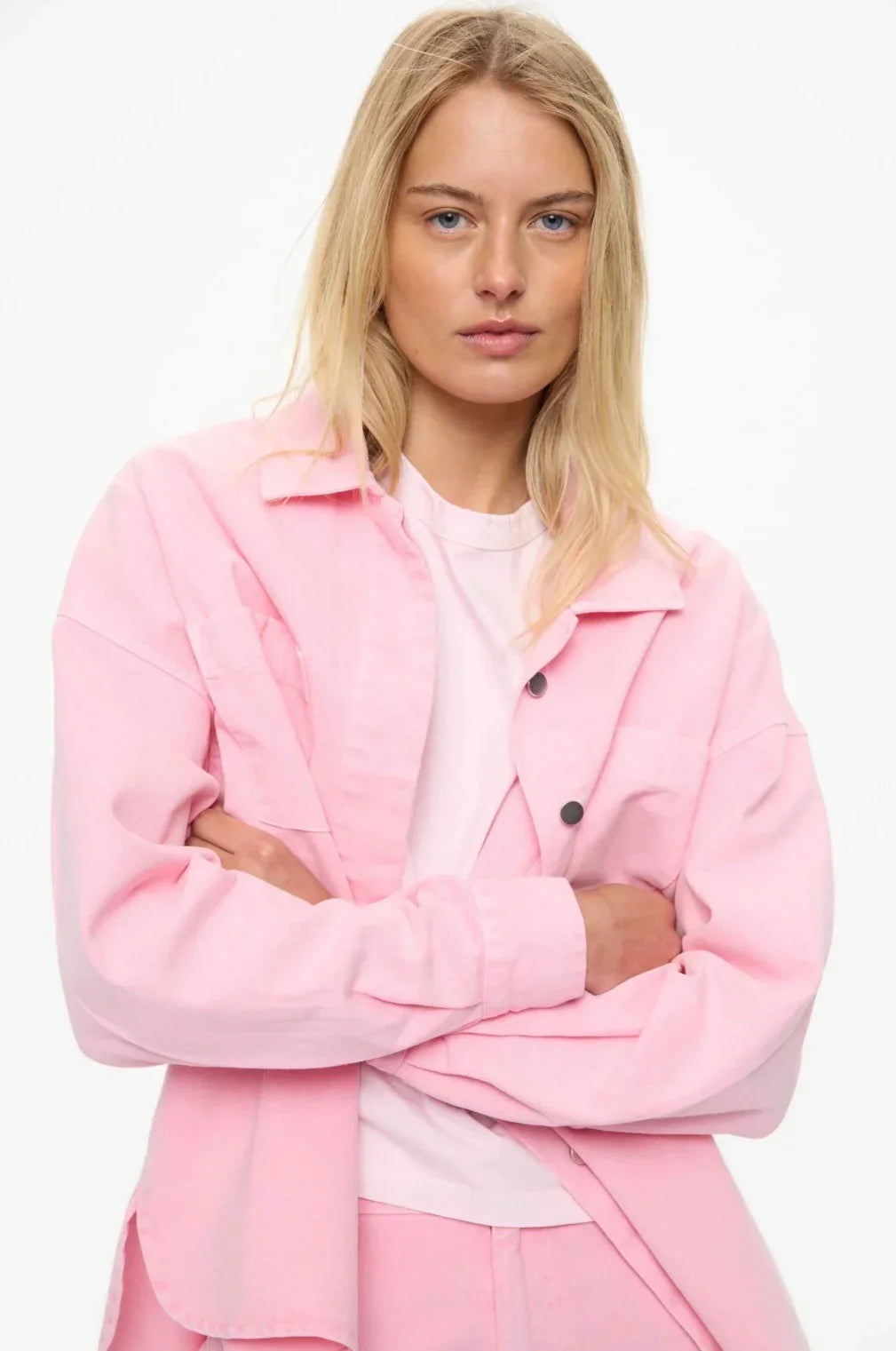 Blonde woman in pink oversized jacket and matching pants, styled with white tee for modern women's fashion