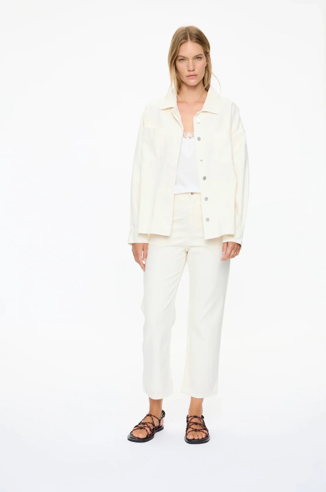 White denim jacket and pants set with lace top and strappy sandals