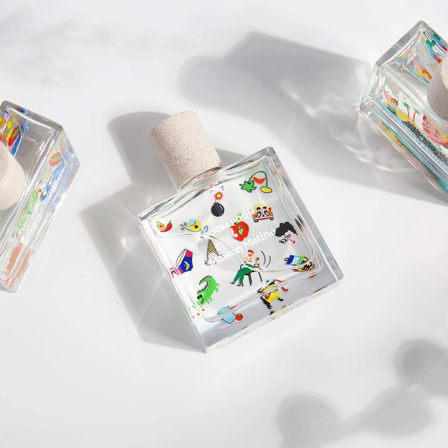 Clear glass perfume bottle with colorful playful illustrations and cork stopper, stylish fragrance for women