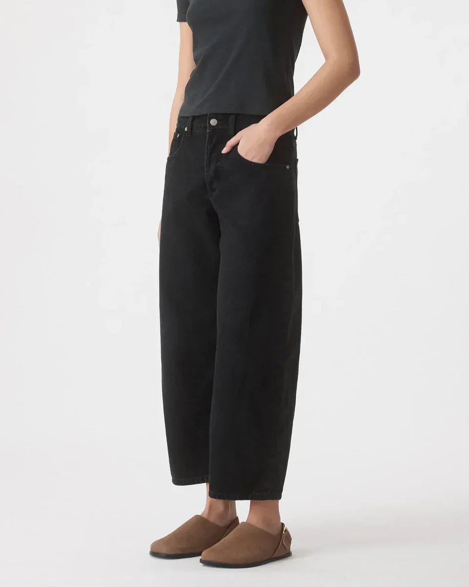 Black wide-leg cropped jeans with relaxed fit, paired with brown slip-on shoes for casual style