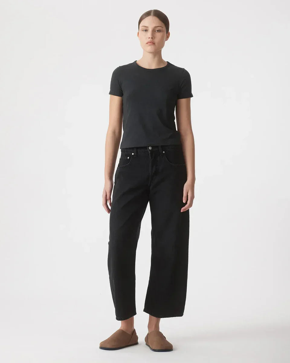 Woman in black tee and wide-leg cropped jeans with brown slip-ons, minimalist fashion