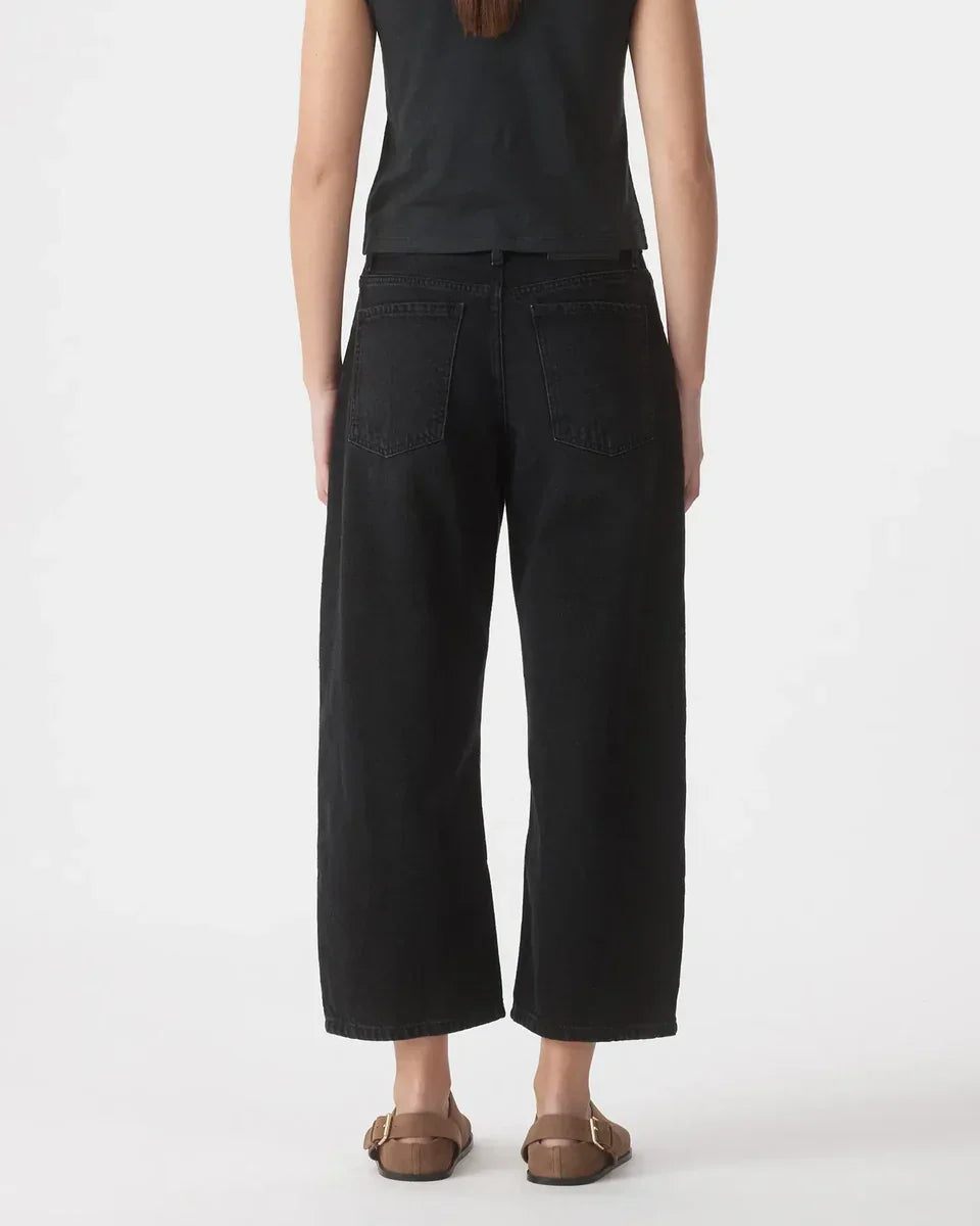 Black wide-leg cropped jeans with back pockets, paired with brown sandals for casual chic style.