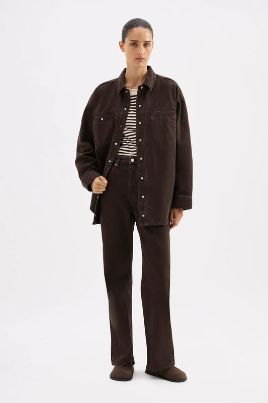 Woman modeling dark brown oversized denim shirt and matching straight-leg jeans with striped top