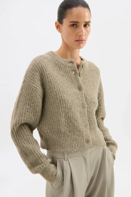 Woman wearing cozy beige ribbed knit cardigan with buttons, paired with matching trousers for a chic autumn look.