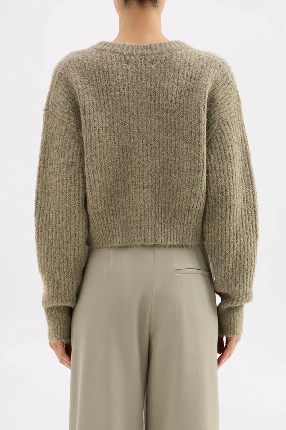 Olive ribbed knit sweater with long sleeves paired with light gray wide-leg pants