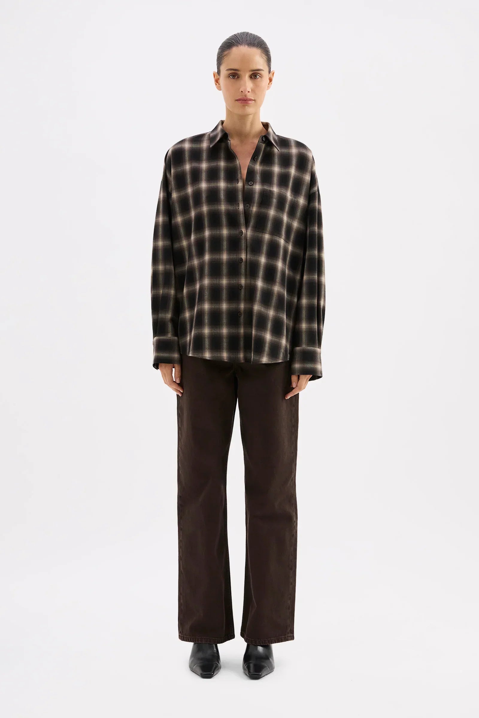 Woman in black and beige plaid shirt with wide-leg brown pants and black boots