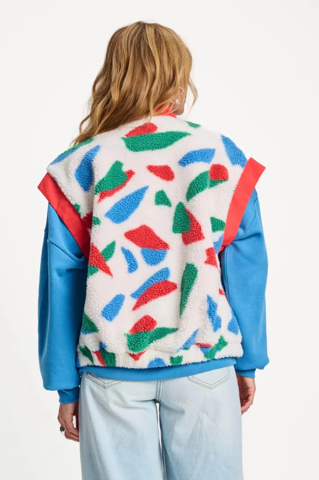 Colourful abstract patterned sherpa bomber jacket with blue sleeves and red accents, back view