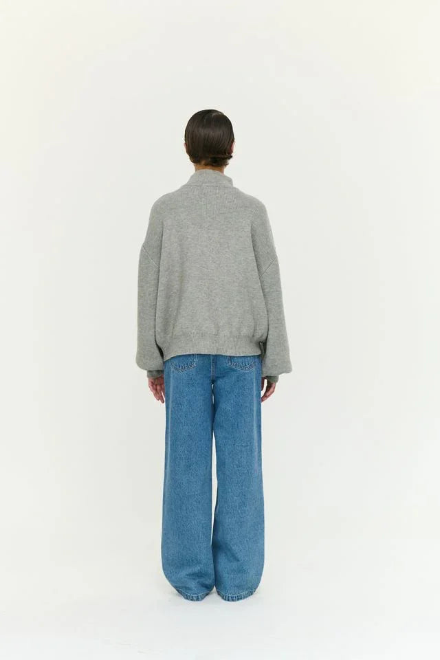 Woman in grey oversized sweater and wide-leg blue jeans, back view